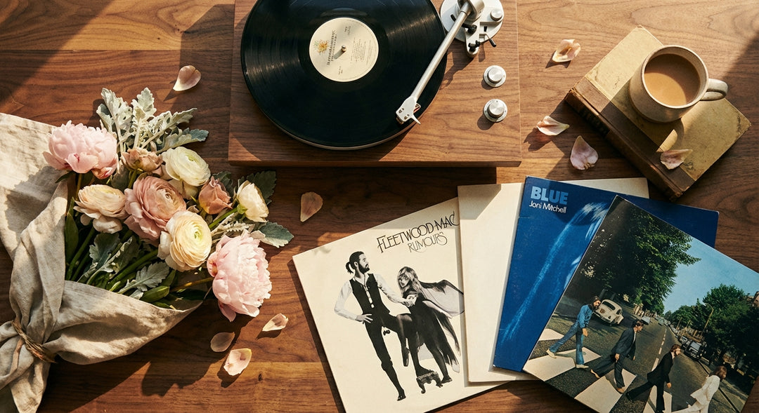 A modern turntable resting on a wooden surface beside a bouquet of blush peonies and vinyl records, bathed in warm golden light.