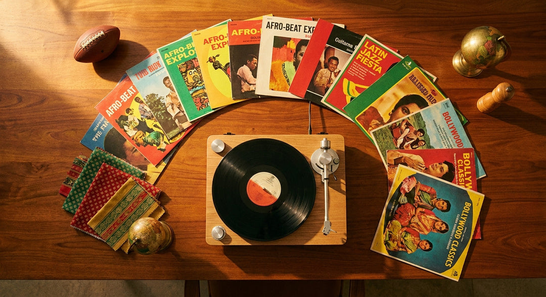 A warm flat-lay of colorful vinyl records fanned around a modern turntable on a wooden surface, accented with a small football and vibrant global textiles, evoking an international music celebration.